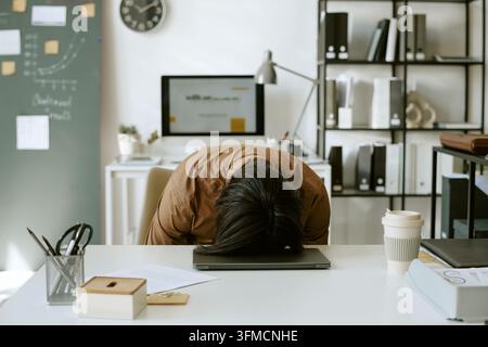 Exhausted Businessman Sleeping on Laptop at Office Desk Stock Photo