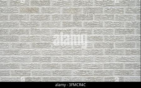 White painted textured brick wall with rough, uneven brick faces in a horizontal composition, showing a staggered running bond pattern Stock Photo
