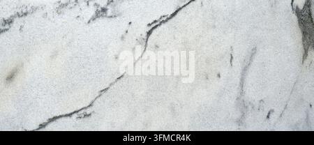 White veined granite with directional gray and black mineral veins, quartz crystals, flowing dark bands, mineral clusters, and a large black splotch Stock Photo