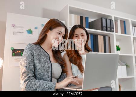 Two businesswomen collaborating on reports and performance charts, discussing business strategy, reviewing data analysis, presenting results, and plan Stock Photo