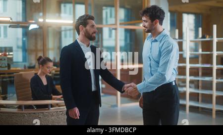 Two Caucasian business men shaking hands meeting in office. Businessmen males workers handshake friendly talking corporate partners smiling shake arms Stock Photo