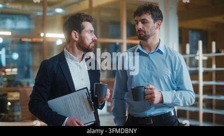 Two friendly calm Caucasian business men talking drinking coffee break pause in office. Relaxed businessmen male partners talk drink tea together Stock Photo