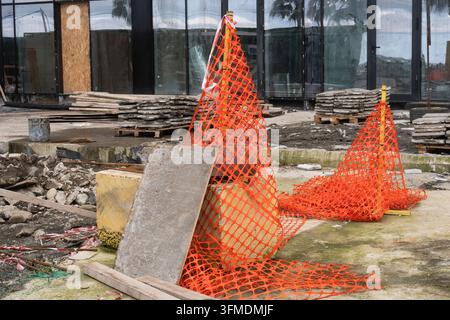 Construction safety site with orange plastic mesh fence barrier and concrete blocks outdoor. Stock Photo