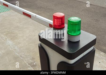 Automatic parking barrier post with green and red signal warning lights at driveway entrance. Stock Photo