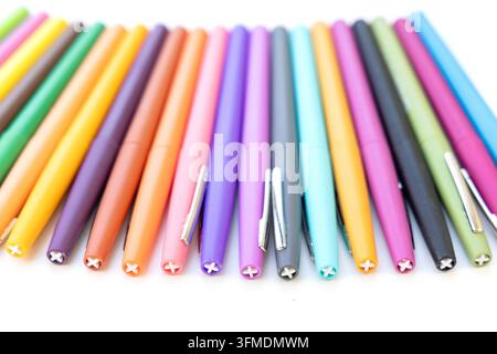 Bright colored pens lie neatly arranged on a flat surface Stock Photo