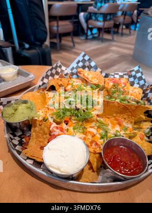 Loaded nachos served with sour cream, salsa and guacamole at a restaurant in Halifax Stanfield International Airport. Stock Photo