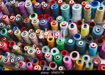 Rows of colorful sewing thread spools are displayed in a clothing alterations shop. Stock Photo