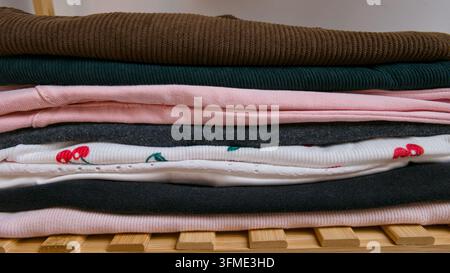 Neatly folded clothes stacked on wooden shelves in a modern wardrobe closet, home organization and storage concept, casual apparel and textiles interi Stock Photo