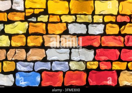 Close-up on a church mosaic featuring vivid glass tiles in various colors including red, yellow, orange and more with each tile having a unique textur Stock Photo