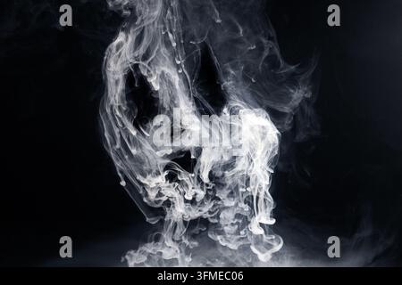 White smoke dissolving in dark water Stock Photo