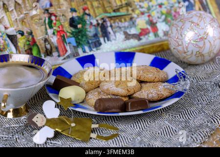 Orange cookies with chocolate candy on plate and cup of coffee, arranged with golden angel figure, silver stars, Christmas ball and advent calendar Stock Photo