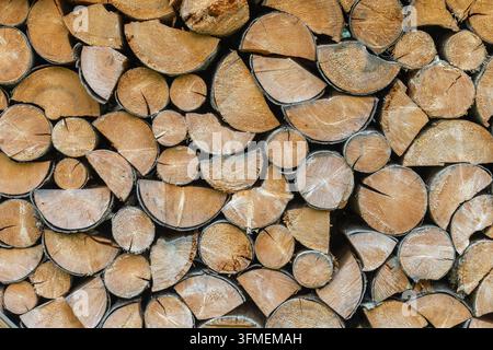 Detailed full frame view of split firewood logs stacked outdoors. The wood grain and bark textures highlight winter energy preparation Stock Photo