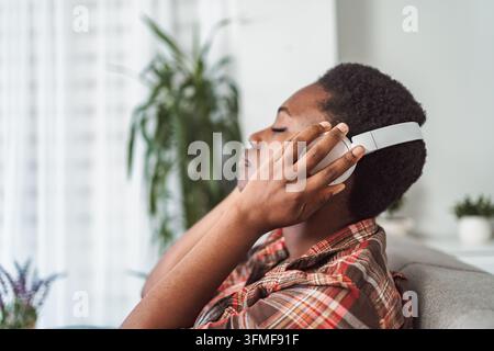 Young woman relaxing on sofa enjoying music with headphones Stock Photo