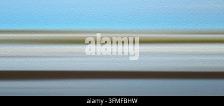 Blue sky stretches wide across frame. Smooth bands of green, white, brown run horizontally. soft blur creates sense of smooth, fluid motion. abstract Stock Photo