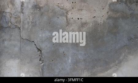 Texture of old gray concrete with deep cracks and potholes. A gloomy grunge background featuring a porous cement structure, traces of erosion and damp Stock Photo