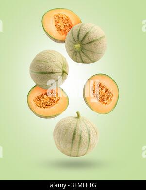 Fresh cantaloupe melons falling on pastel green background. Whole and sliced Stock Photo