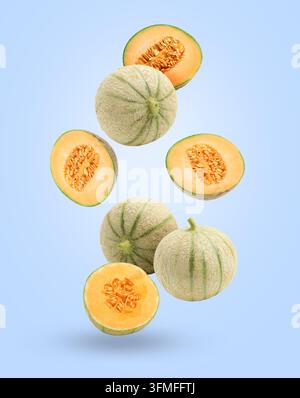 Fresh cantaloupe melons falling on pastel blue background. Whole and sliced Stock Photo