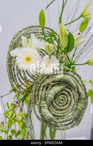 Floral bouquet in a handwoven basket, green and white materials, intricate spiral pattern, natural beauty, minimalist background, soft lighting, balan Stock Photo