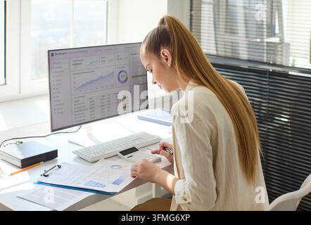 Focused woman analyzing finance data on marketing analytics dashboard at office Stock Photo