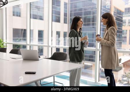 Multicultural female colleagues chatting in conference room of modern office Stock Photo