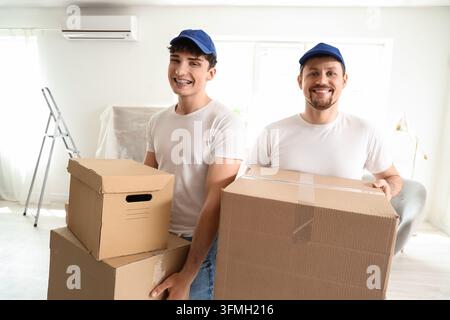 Moving service and relocation assistance, professional movers carrying cardboard boxes into a new home for residential relocation and logistics suppor Stock Photo
