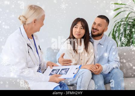 Pregnancy consultation and prenatal care, doctor showing ultrasound scan to happy expectant couple during winter holidays in a medical office Stock Photo
