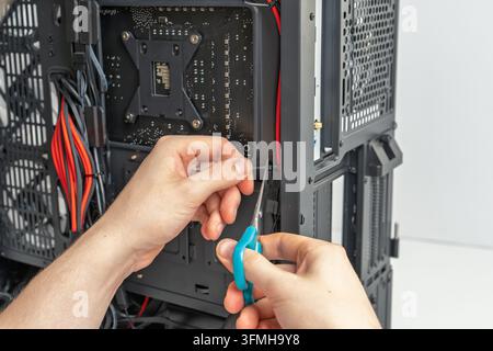 Close up view of a technician using scissors to trim excess plastic cable ties while building a custom desktop computer. Professional cable management Stock Photo
