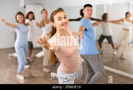 Smiling young adult couples dancing together in pairs and practicing movements in modern choreography class Stock Photo