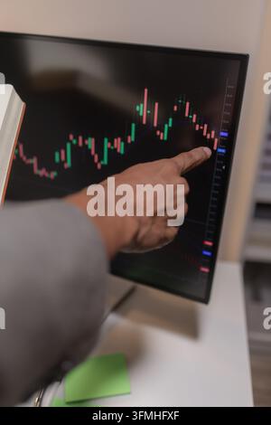 Professional financial analyst reviewing stock market charts across multiple screens using a tablet, laptop and calculator to evaluate price movements Stock Photo
