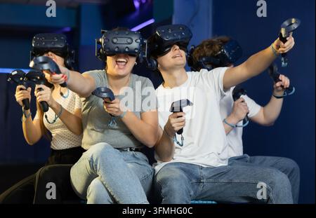 Modern people wearing virtual reality headset playing video games together Stock Photo