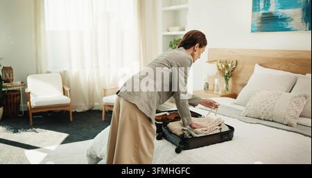 Woman, packing and suitcase at house for travel, preparation and clothing for holiday adventure. Female person, sorting and luggage in bedroom for Stock Photo