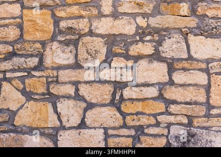Textured stone wall with dark mortar joints background Stock Photo