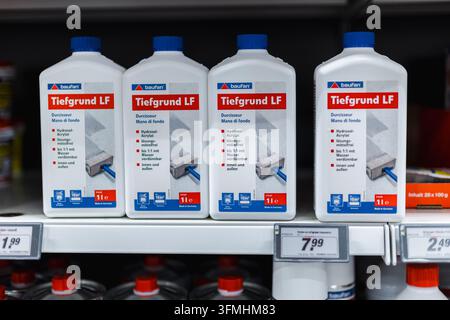 Iserlohn, Germany, August 17, 2026: Four white primer bottles are displayed on a hardware store shelf German labels read Tiefgrund LF, meaning deep Stock Photo