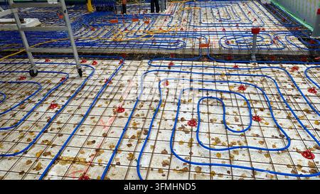 Underfloor heating pipes installed over reinforcement mesh at construction site Stock Photo