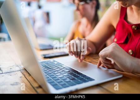 close up of hands of focused young woman typing on keyboard doing remote work on laptop at outdoor terrace as digital nomad Stock Photo