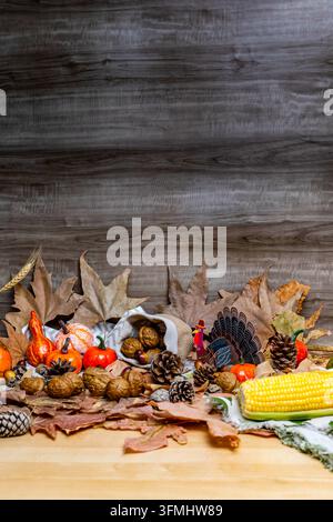 Thanksgiving arrangement showcasing autumn leaves, gourds, walnuts, pinecones, and corn on a rustic wood background Stock Photo