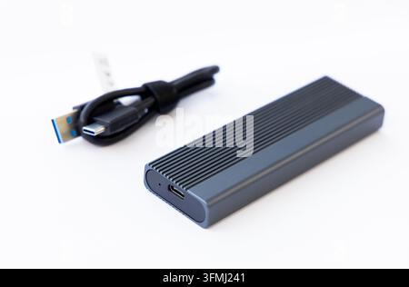 An external solid state drive sits next to its connecting cord Stock Photo