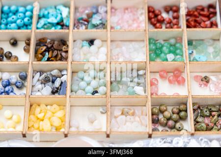 A wooden box holds many colorful gemstone beads Stock Photo