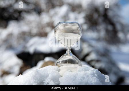 Conceptual image of switching to winter time or fall back, end of daylight saving time. Selective focus on hourglass with white color sand falling. Stock Photo