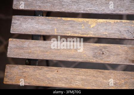 Weathered wooden slats with worn paint and metal support, close-up showing peeling flakes, small cracks, and muted patina tones for rustic background Stock Photo