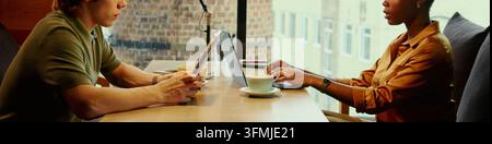 Header of Diverse Colleagues Working on Laptop and Digital Tablet in Cafe Stock Photo