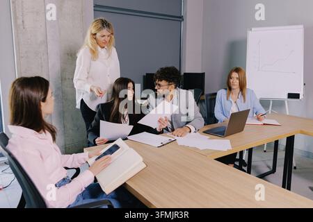 Diverse group of professionals discussing documents and ideas during a company meeting in a modern office environment Stock Photo