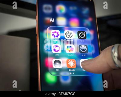 Finger touching smartphone screen with folder of AI app icons including ChatGPT, Claude, Meta AI, Grok, Copilot, and Siri Stock Photo