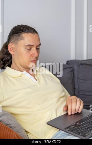 Middle aged man focused on laptop during remote work at home. Concept of time management, productivity tracking, digital workplace, remote work and fl Stock Photo