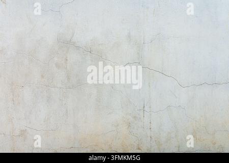 A close up view of a weathered white concrete wall featuring fine structural cracks stains and a distressed plaster finish Stock Photo