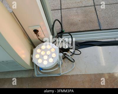 LED stage light with multiple bulbs standing on floor near power outlet and glass door. Stock Photo