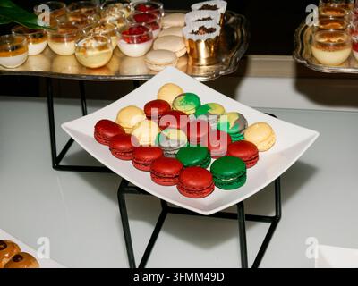 Plate of colorful macarons displayed on a white square dish at a dessert buffet. Stock Photo