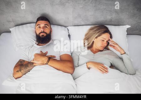 Couple is lying in bed. They are angry and not talking to each other. Stock Photo