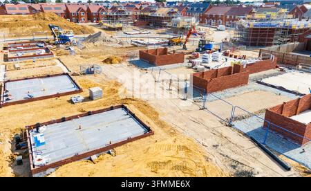 Elevated drone view of  a new build housing estate under construction with brickwork and foundations Stock Photo