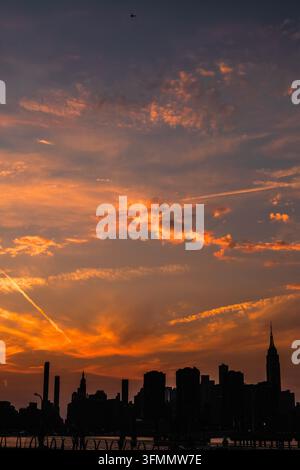 A fiery orange sunset silhouetting the Manhattan skyline across the river, New York City Stock Photo